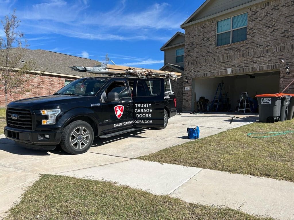 a black trusty garage door repair truck parked in front of a house